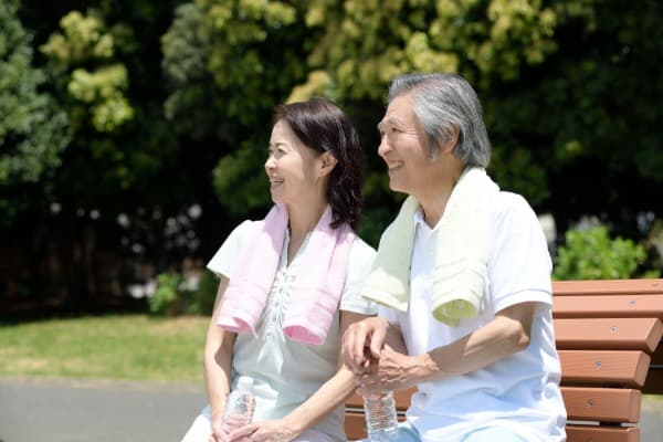 ウォーキング中に水を飲み会話をする夫婦の画像イメージ